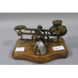 A set of brass postal scales and weights on mahogany base
