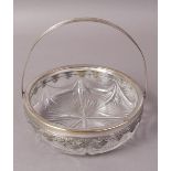 A SILVER PLATED AND CUT GLASS BASKET, circular with swing handle, the rim with pendant anthemion,