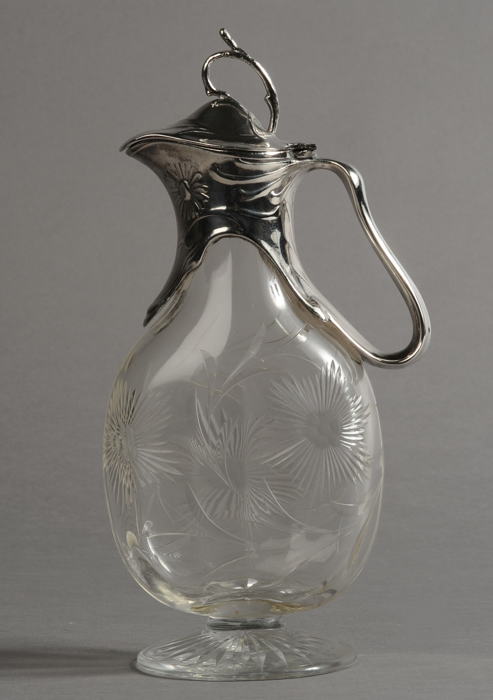 AN ART NOUVEAU SILVER PLATE MOUNTED CRYSTAL GLASS EWER, having a twig finial to the domed cover,