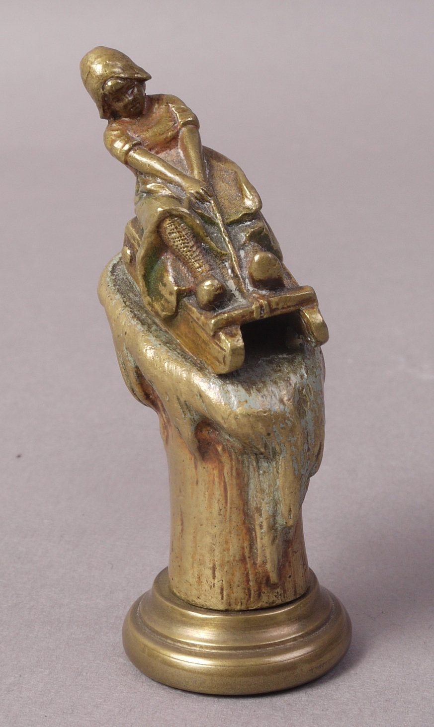 A LATE VICTORIAN GILDED BRONZE DESK SEAL OR STAND, modelled as a girl on a wooden sledge,