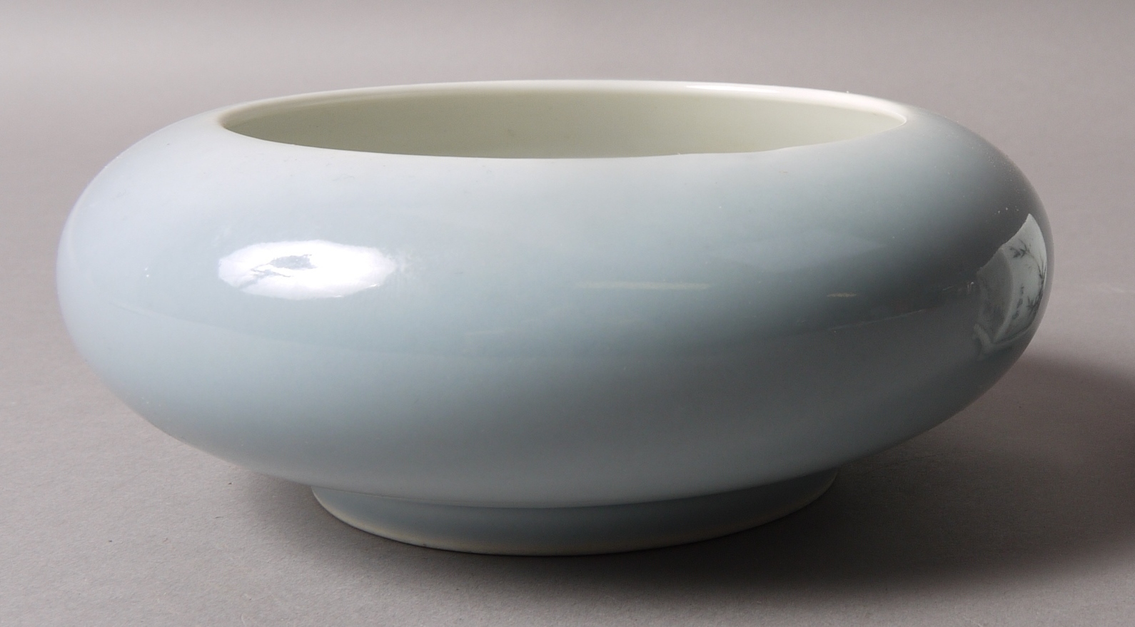 A CHINESE PORCELAIN SHALLOW BOWL with everted rim, pale blue graduated glaze,