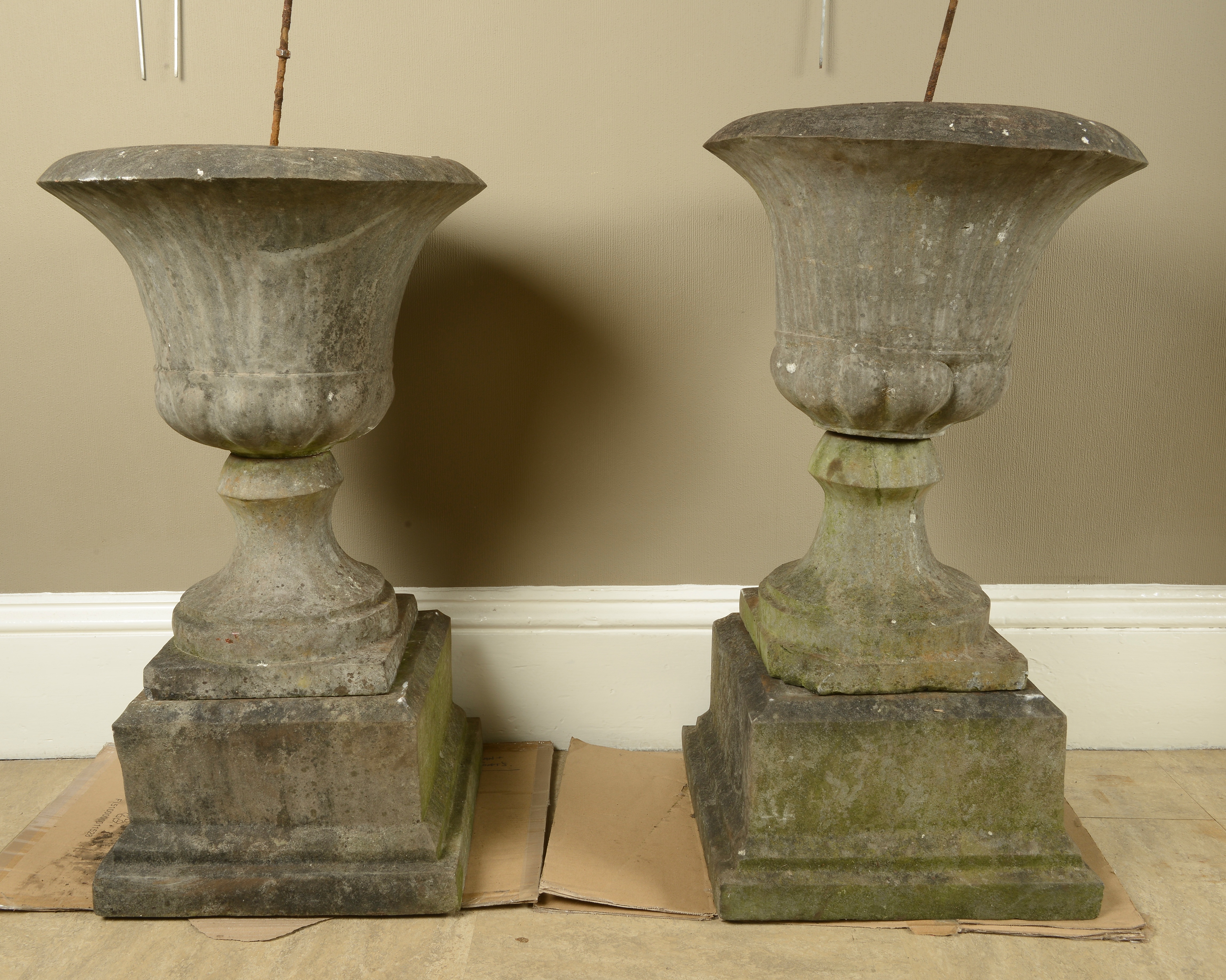 A PAIR OF 19TH CENTURY GRITSTONE GARDEN URNS of campana form on waisted socles and stepped square