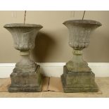 A PAIR OF 19TH CENTURY GRITSTONE GARDEN URNS of campana form on waisted socles and stepped square