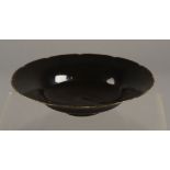 A CHINESE BLACK GLAZED DISH of circular petal form,
