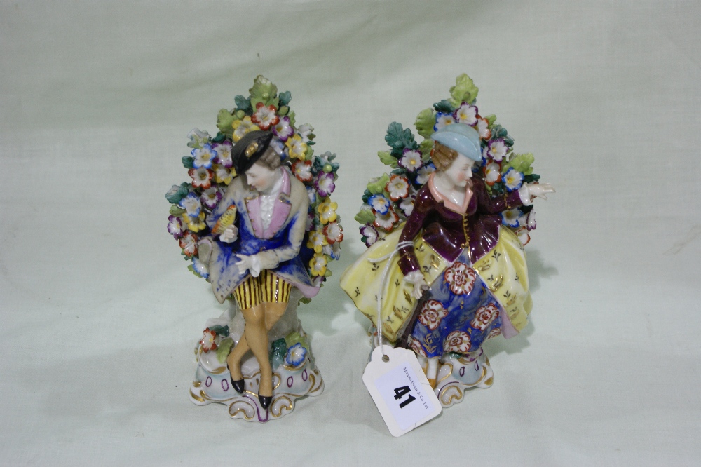 A Pair Of 19th Century Continental Porcelain Figures In The Meissen Style, Each Seated Against A