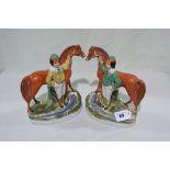 A Pair Of Staffordshire Pottery Figures Of Jockeys Standing By Race Horses