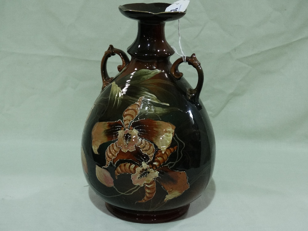 A Continental Pottery Circular Based Two Handled Vase, The Green/Brown Ground Decorated With Flowers