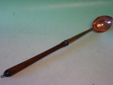 A Copper Straining Spoon With turned treen handle. 18th century. 20" long