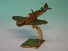A Brass Spitfire Desk Weight Raised on a stand. 6" wingspan.