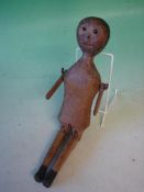 A Primitive Wooden Peg Doll Traces of original paint. Jointed at shoulders and knees, Glass eyes.