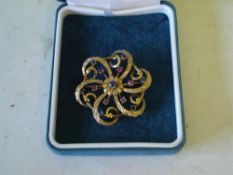A Gold Openwork Scroll Brooch Set with sapphires and rubies. One vacant setting.