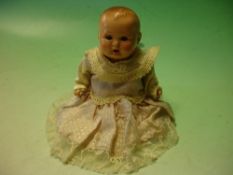 A German Baby Doll. The porcelain head with sleeping eyes and open mouth, composition body and