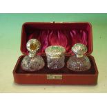 A Cased Dressing Table Set. The pair of cut glass Cologne bottles with repousse silver lids and