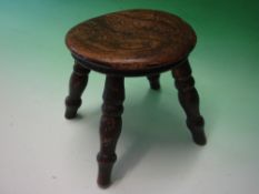 A Welsh Milking Stool. The moulded round top raised on splayed turned legs. 7 ¾" diam