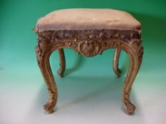 A French Giltwood Stool. Carved with shells and flower heads, raised on acanthus moulded cabriole