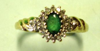 An Emerald and Diamond Cluster Ring Each shoulder set with three diamonds. In gold marked 375.