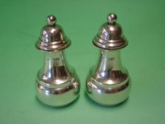 A Pair of Silver Pepperettes The domed covers with ball finials. 3 ¼" high. Chester 1909.