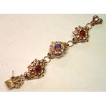 A 14ct Gold Bracelet Formed as three linked flower heads, set with an amethyst and two smoky