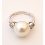 ATTRACTIVE PEARL AND DIAMOND RING
the central pearl flanked by diamond clusters,