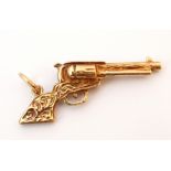 NINE CARAT GOLD PENDANT
in the form of a revolver, with scroll decoration to the handle and barrel,