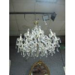 A TWELVE BRANCH CUT GLASS CHANDELIER with scroll arms and circular drip pans hung with faceted