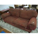 A VICTORIAN STYLE SETTEE with loose cushions and scroll arms on bun feet with brass casters 212cm