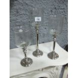 A SET OF THREE GRADUATED CANDLE HOLDERS each with a cylindrical turned column raised on a circular