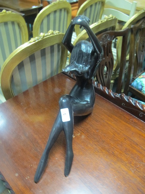 AN ART DECO BRONZE FIGURE modelled as a naked female shown seated with arms raised 43cm (h) x 38cm