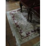 A WOOL RUG the beige ground with central floral panel within a wine floral border 203cm x 134cm