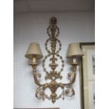 A PAIR OF GILT TWO BRANCH WALL SCONCES each with a husk and urn decorated back plate issuing two