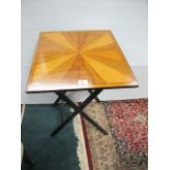 A FOLDING TABLE with segmented top raised on ebonised folding stand