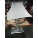 A CLEAR GLASS AND CHROME DESIGNER TABLE LAMP the rectangular stepped column raised on a rectangular