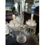 A CUT GLASS TWO BRANCH CANDELABRA with pendant drops