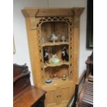 A PINE CORNER CABINET the moulded cornice above three open shelves with pierced fretwork decoration