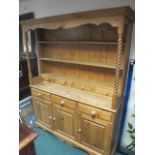 A PINE DRESSER the moulded cornice above three open shelves with four short drawers the base with