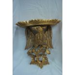 Pair of carved gilt wood wall brackets with shaped tops, eagle support, C scroll and foliate