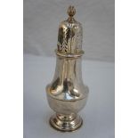 An Edwardian silver sugar shaker in the Georgian style with flame finial dome lid, belted baluster