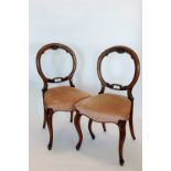 A set of four Victorian walnut balloon back dining chairs with rococo scroll carved splat backs,