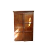 A Victorian mahogany wardrobe with dentil pediment and twin panelled doors opening to reveal an