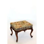 A Victorian walnut stool with needlework seat, shell and rococo scroll carved frame, on cabriole