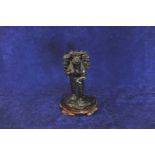 An oriental bronze figure of a gentleman carrying a bundle of sticks whilst reading a book, with
