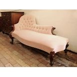 A Victorian chaise longue with puce upholstered button back, stylised flower head and acanthus