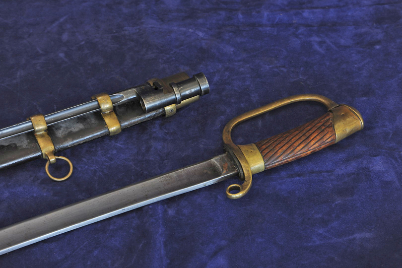 A Russian 1917 cavalry sword with 31½ins blade, wooden grip and brass hilt together with its black