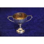 A George V silver trophy cup with twin angular handles, tapering stem and out-splayed circular foot.