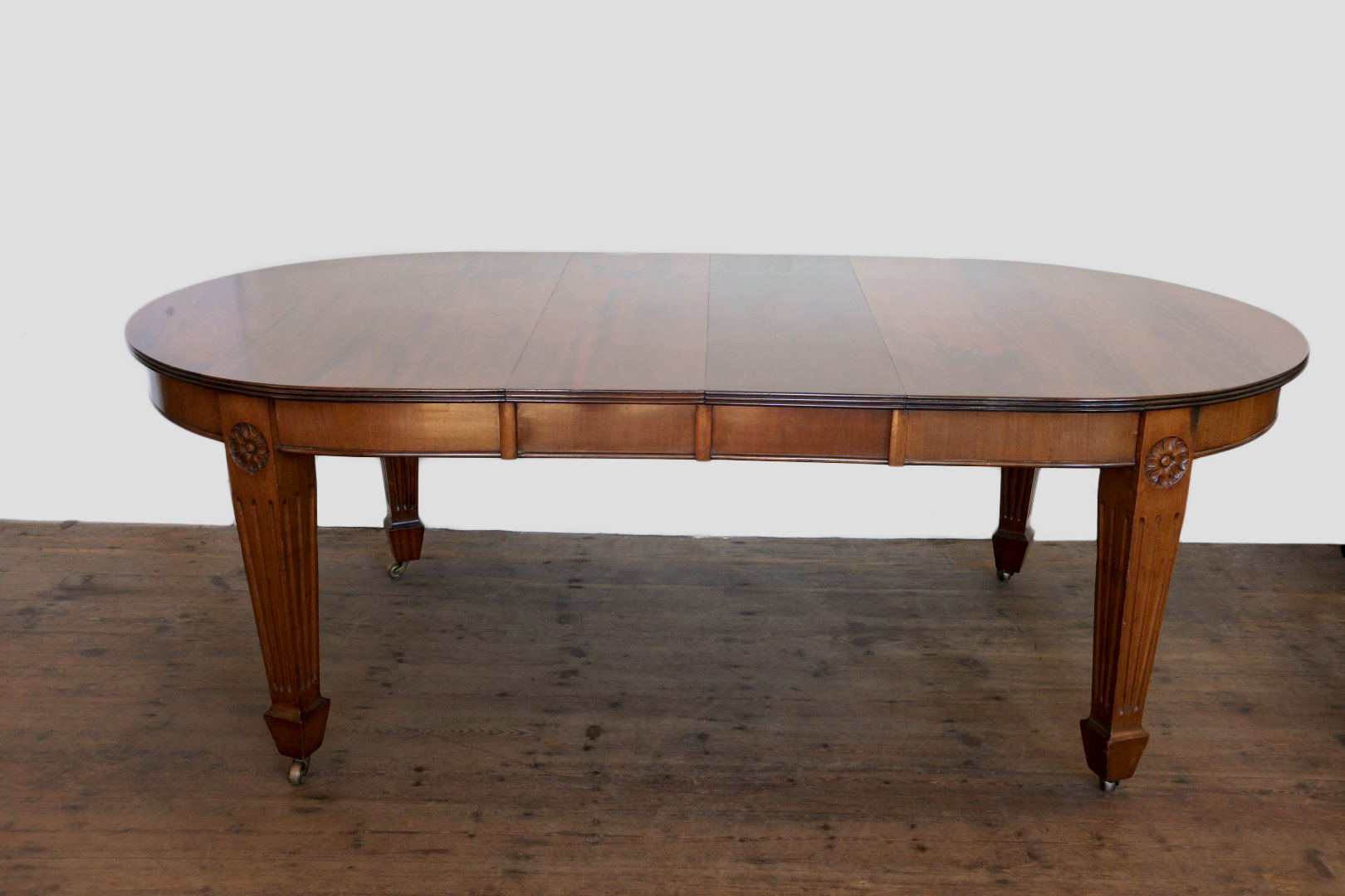 A late Victorian/early Edwardian mahogany extending dining table with reeded frieze and on reeded