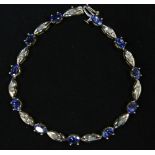 A Tanzanite & Diamond line bracelet, set in 14k gold, eleven oval faceted Tanzanite, each