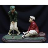 A painted plaster figure group, of Stan Laurel and Oliver Hardy playing golf, on plinth base, 48 x