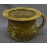 A 17th Century English earthenware pottery chamber pot, with mottled pale green glaze and loop