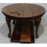 An Edwardian stained walnut extending oval dining table, with two extra leaves and winding handle,