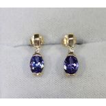 A pair of 14k gold, Tanzanite and diamond bar drop earrings, each set with an oval mixed cut